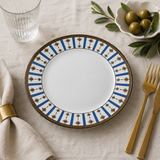 Porcelain dinner plate with blue and gold star pattern styled on a neutral table setting with gold cutlery, linen napkin, and olives for an elegant dining look