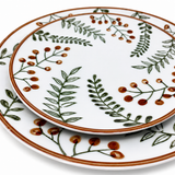 Stacked ceramic plates with green leaf and orange berry botanical pattern, minimalist decorative dinnerware set on white background