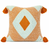 Close up of orange and cream diamond tufted throw pillow with corner tassels and textured woven fabric