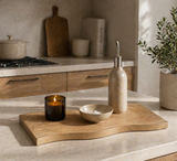 Organic wooden textured decorative tray styled with candle, bowl, and oil dispenser on a modern kitchen countertop with warm natural lighting