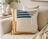 Textured geometric throw pillow with blue and mustard accents on a neutral sofa in a modern cozy living room setting