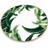 Angled top view of tropical leaf porcelain dinner plate with gold rim on a clean background, modern elegant tableware with green botanical pattern