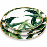 Stacked tropical leaf porcelain dinner plates with gold rim on a clean background, modern elegant tableware set with green botanical pattern